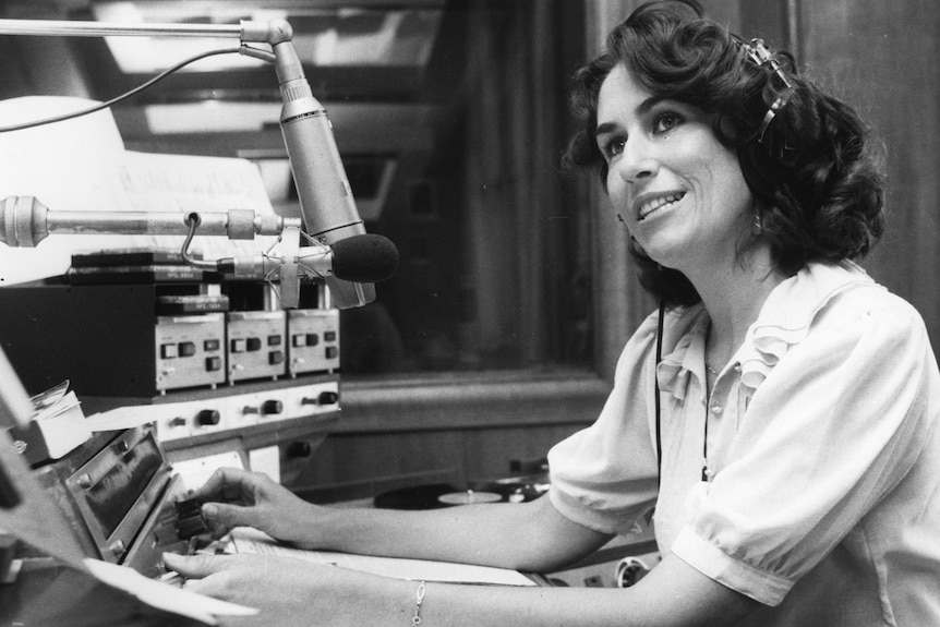 A black and white photograph of Mairi Nicolson wearing headphones and adjusting dials in the studio.