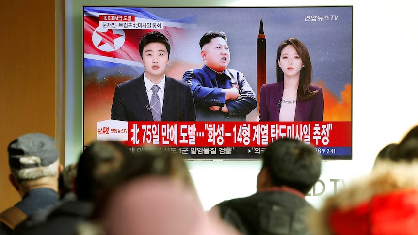 People watch a TV broadcasting a news report on North Korea firing a missile.