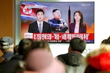 People watch a TV broadcasting a news report on North Korea firing a missile.