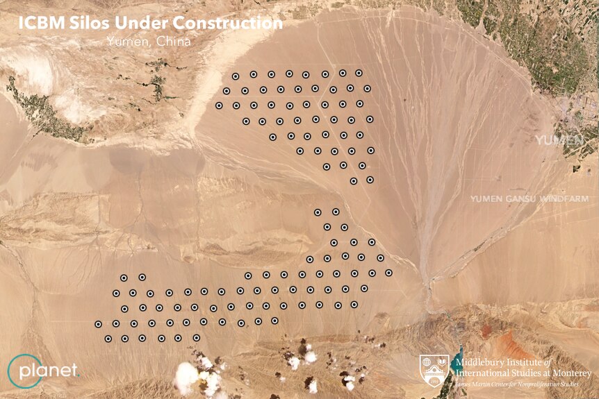 A satellite image of dozens of black dots in an arid environment 