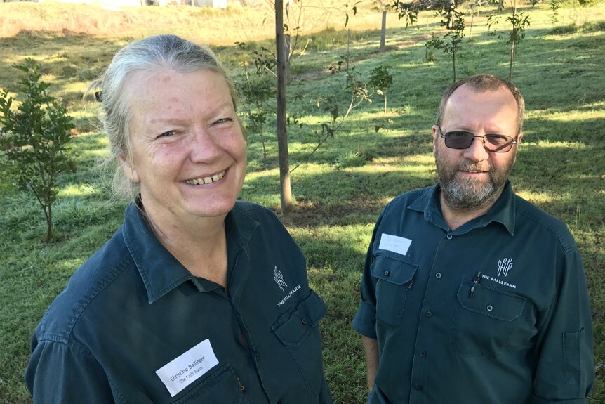 Christine Ballinger and Peter Huddart smile at the camera, standing in front of some trees.