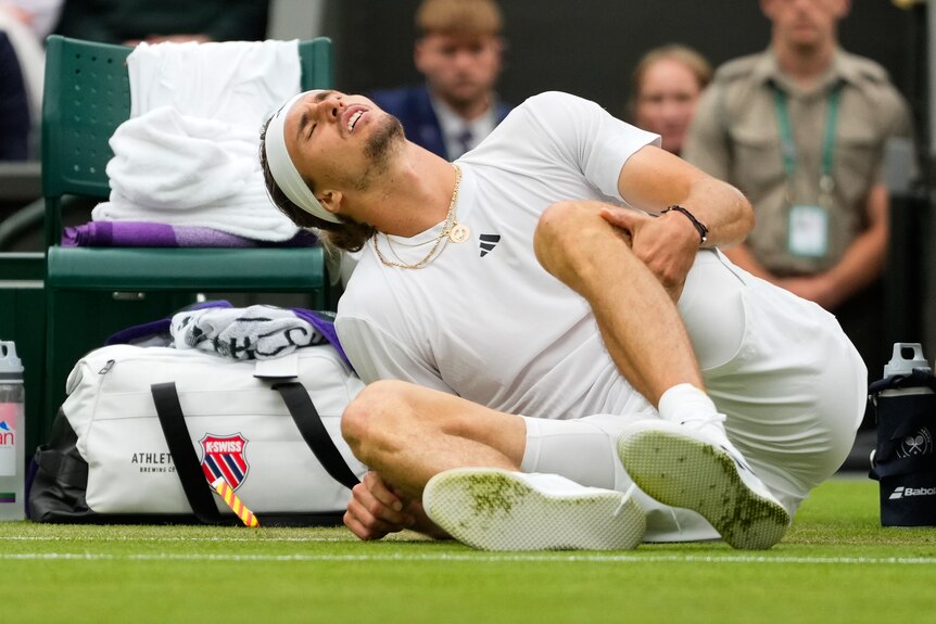Alexander Zverev grimaces on the ground holding his knee
