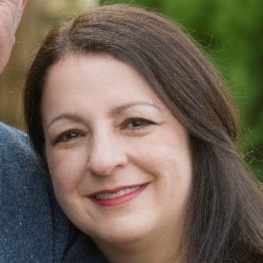 A woman with brown hair pulled back smiling at the camera.