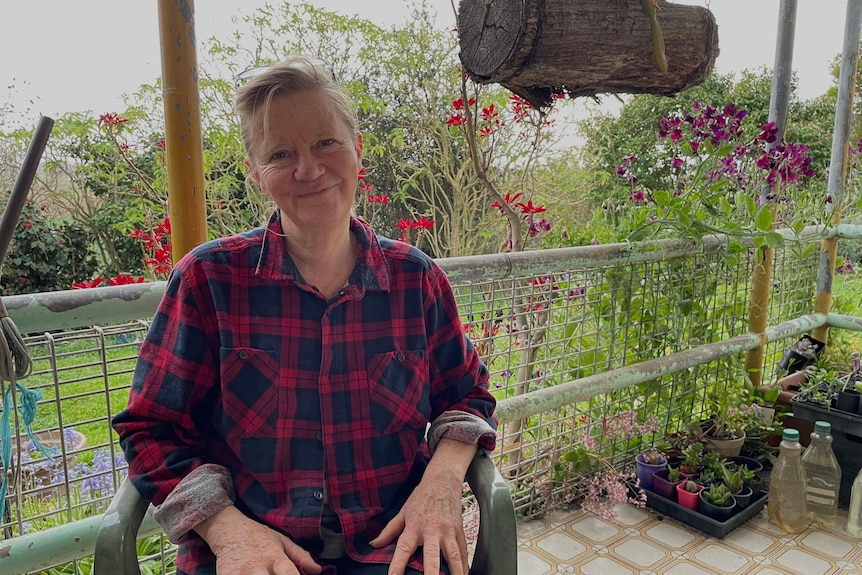 Woman sits on porch in a rural setting