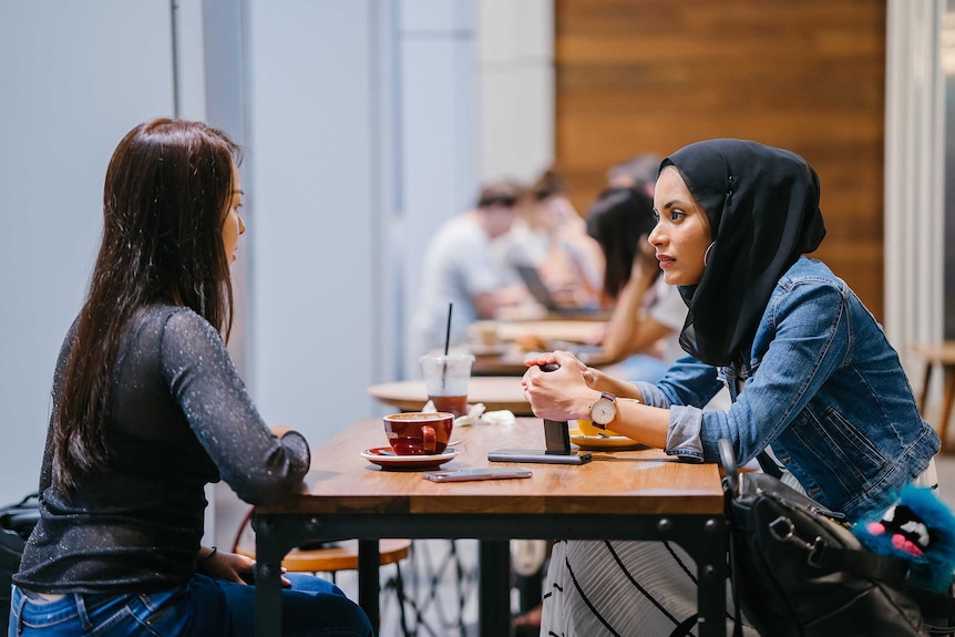 Two people sitting across from one another at a cafe talking