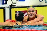 Australian swimmer Kaylee McKeown smiles as she hugs an American rival over the lane rope after a race.