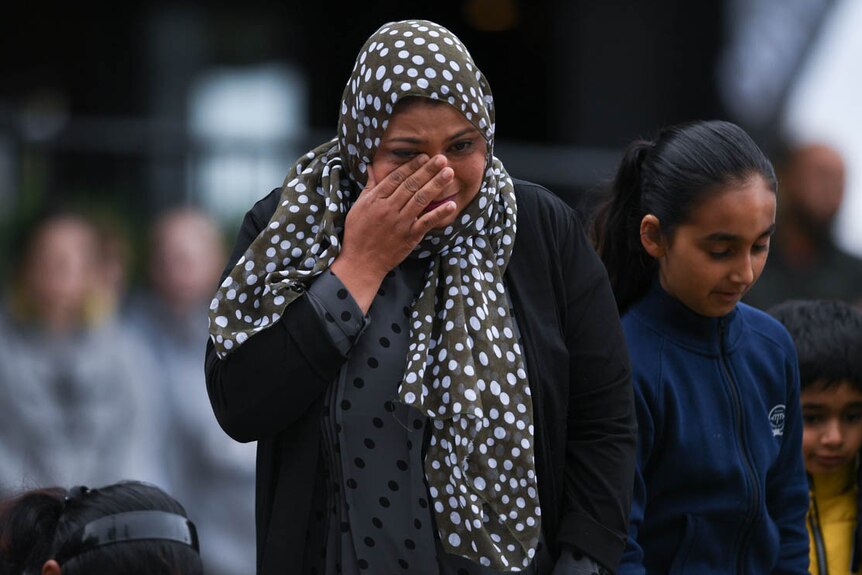 A woman in a headscarf wipes away a tear on Dean's Avenue in Christchurch.