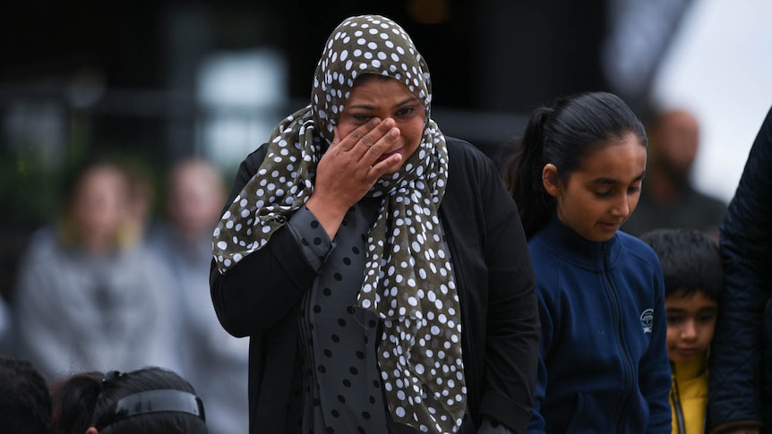 A woman in a headscarf wipes away a tear on Dean's Avenue in Christchurch.