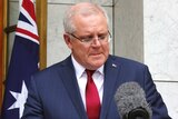 Prime Minister Scott Morrison looks down and bites his lip during a press conference.