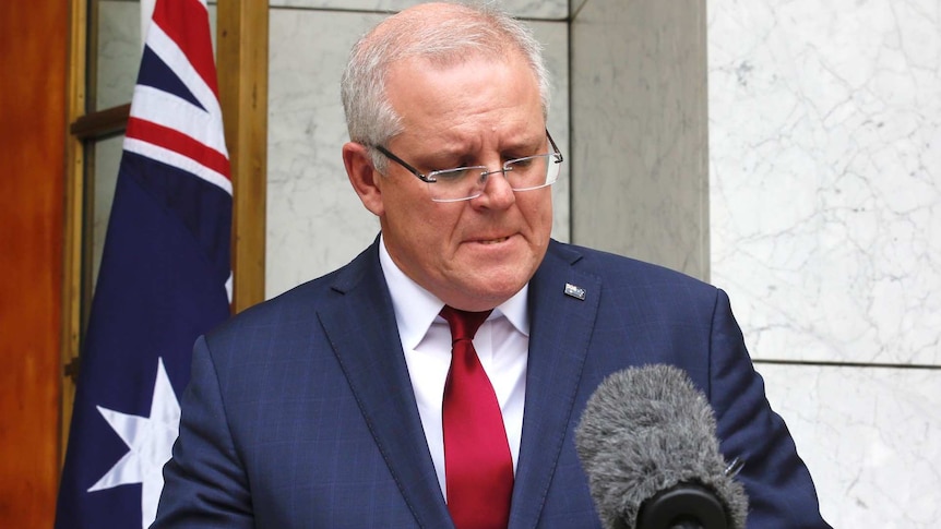 Prime Minister Scott Morrison looks down and bites his lip during a press conference.