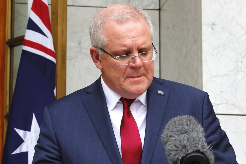 Prime Minister Scott Morrison looks down and bites his lip during a press conference.