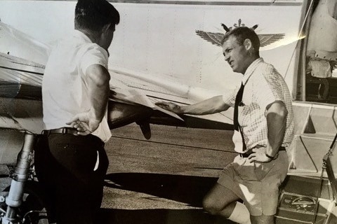 Black and white photo of Dr David Cooke next to the Royal Flying Doctor Service plane.