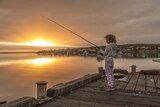 A girl tries to catch fish with her fishing rod off a jetty at Coffin Bay, South Australia.