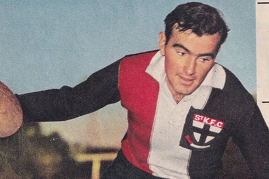 Old photo of football player in red white and black uniform holding leather football