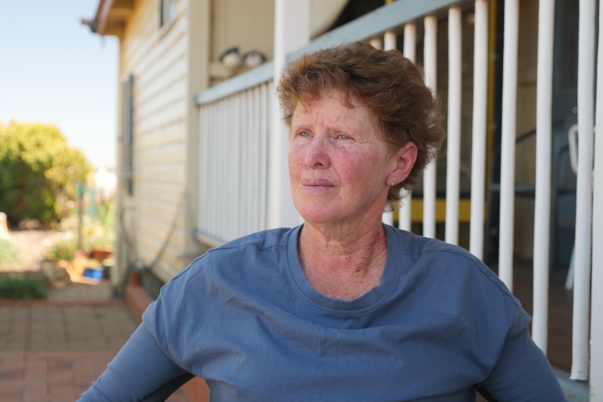 A woman standing in front of a Queenslander-style home.