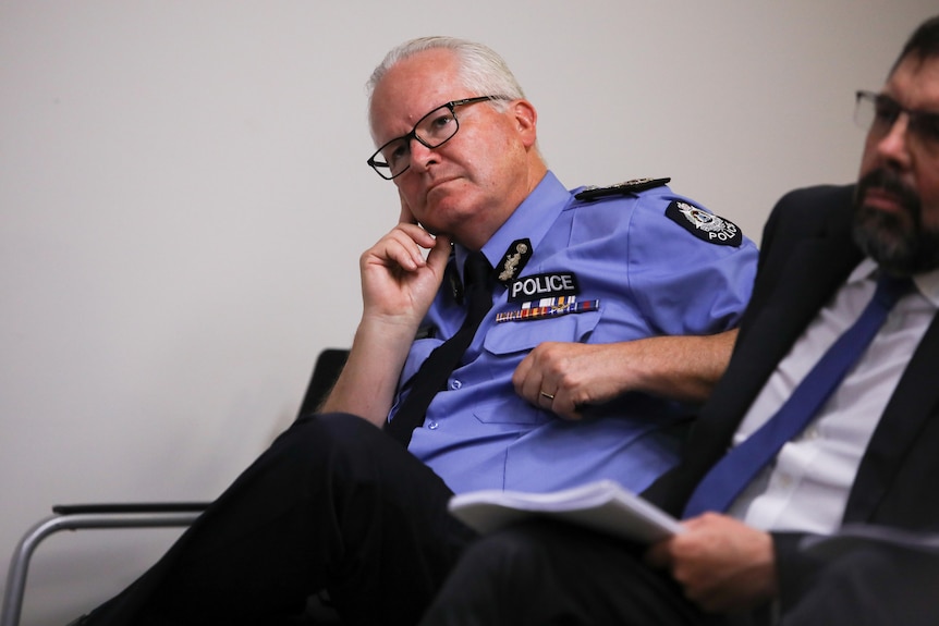 Le commissaire de police Chris Dawson écoute lors d'une conférence de presse.