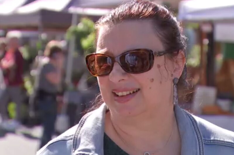A woman in sunglasses at an outdoor market. 