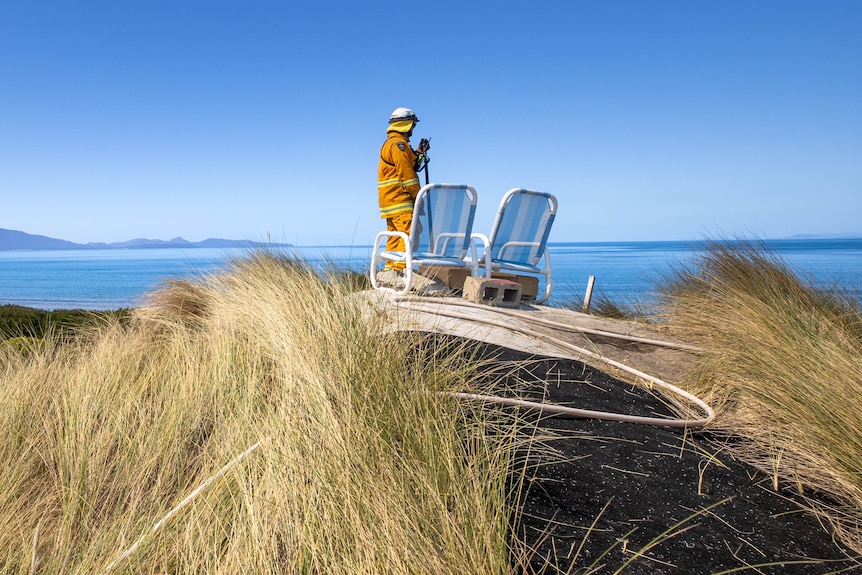 Firefighter on top of a hill near deck chairs overlooking a scenic view.