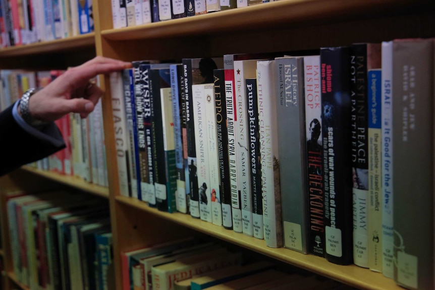 Liberal MP Andrew Hastie thumbs through books in the library at Parliament House.