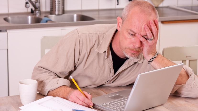 A man looking stressed sitting in front of a laptop computer