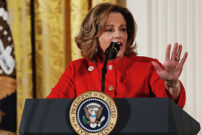 KT McFarland gestures with her hand while speaking at a lectern.
