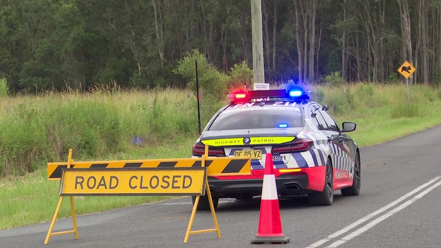 A road closed sign behind a police car on a road