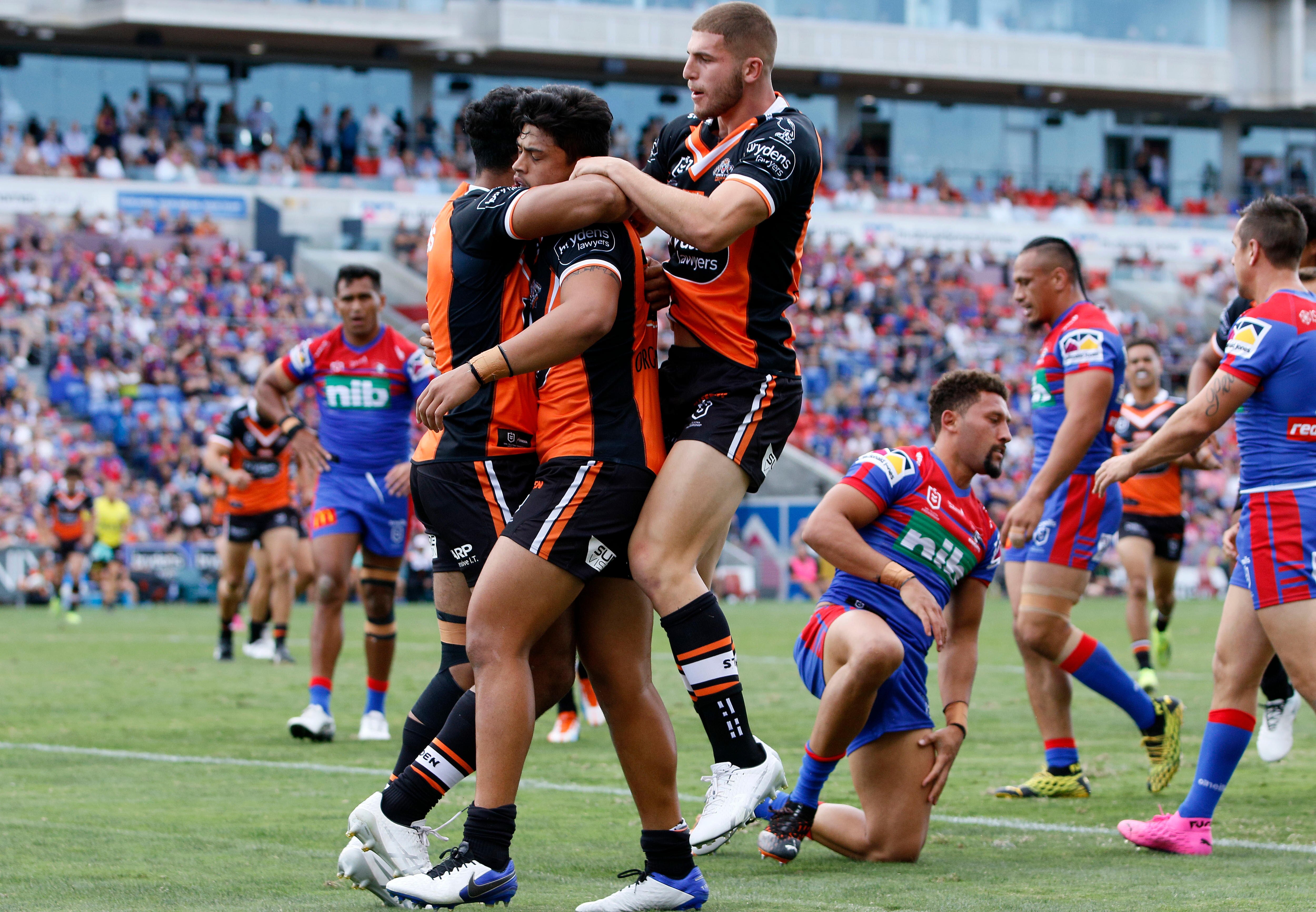 Rugby league players jumping on teammate in celebrating after scoring a try during a match.