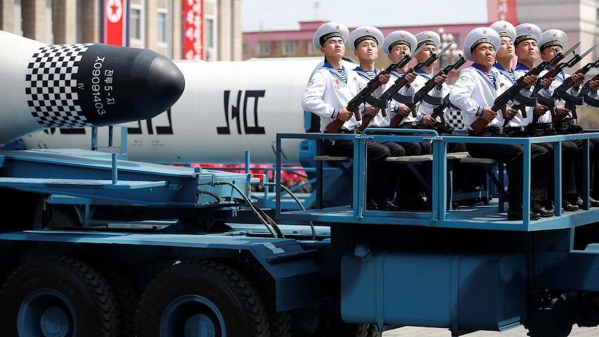 Military vehicles carry missiles with characters reading 'Pukkuksong' during a military parade.