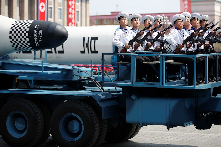 Military vehicles carry missiles with characters reading 'Pukkuksong' during a military parade.