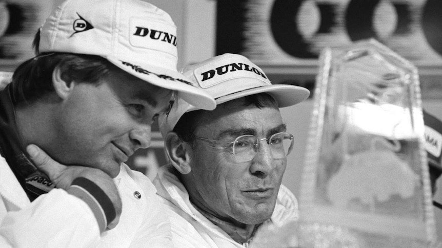 Black and white photograph of racing drivers Greg Hansford and Larry Perkins in Dunlop hats