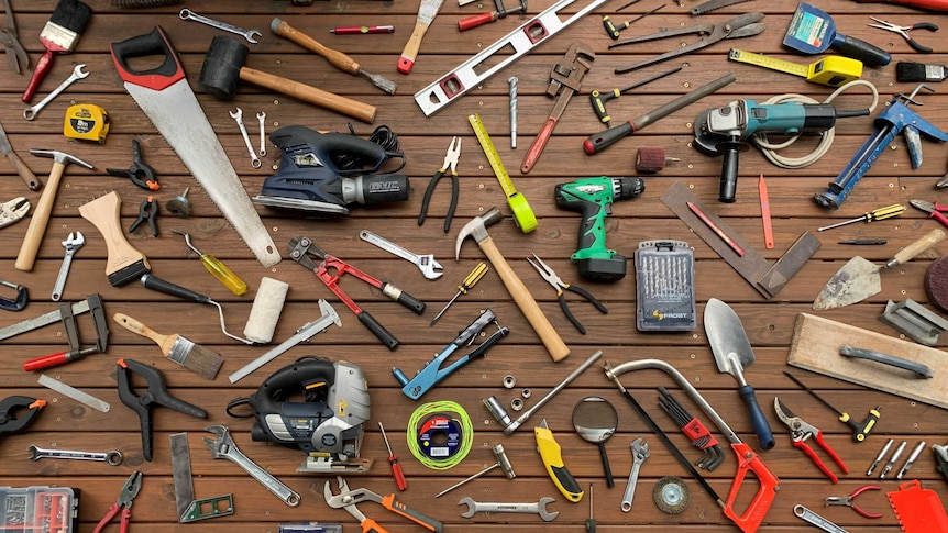 Saws, hammers and other tools from the Gold Coast tool library lie arranged on a deck.