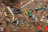 Saws, hammers and other tools from the Gold Coast tool library lie arranged on a deck.