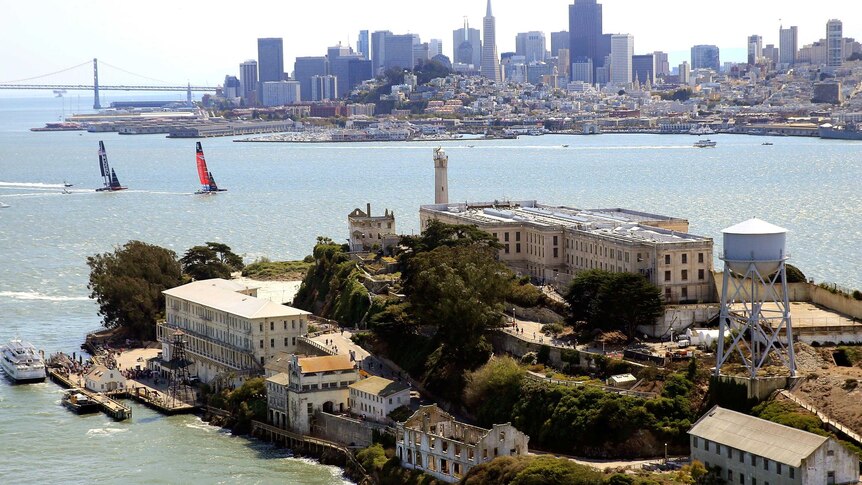 America's Cup yachts sail between Alcatraz and the city of San Francisco.