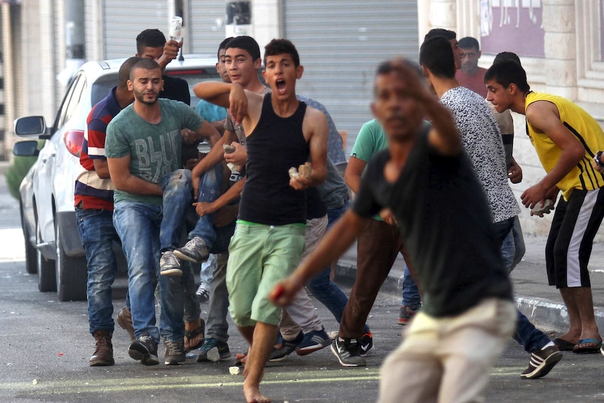Palestinians carry a wounded youth during clashes with Israeli troops