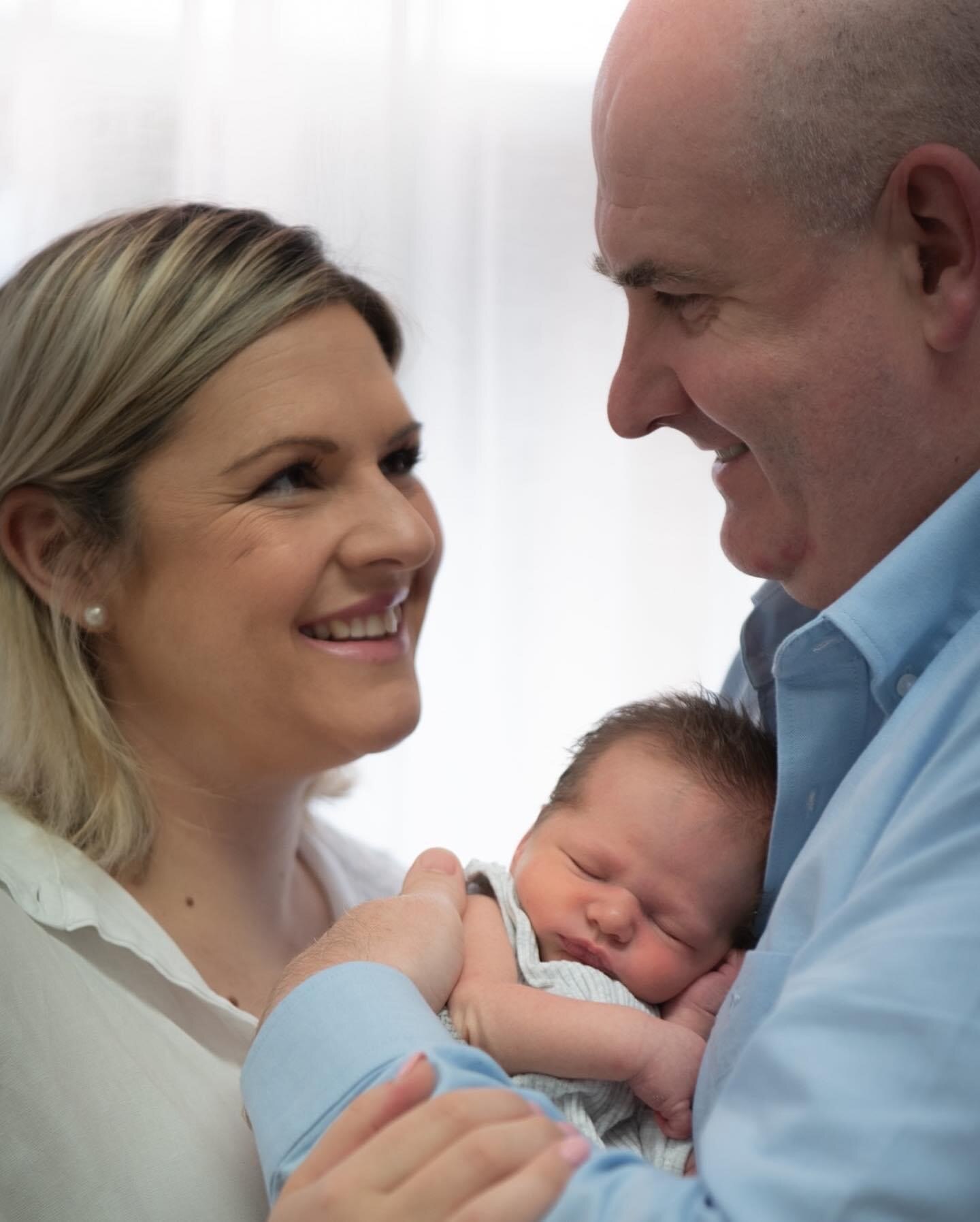 Man, woman and new born baby hugging and smiling