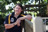 A photo of Invictus Games competitor Sam Gould leaning against a fence, smiling in sunlight.