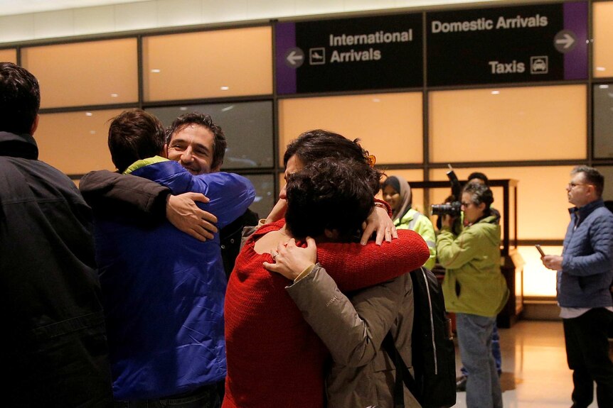 Passengers embrace as they are reunited at the airport.