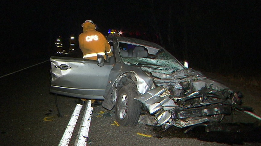 A silver car with its front section destroyed after hitting a tree.