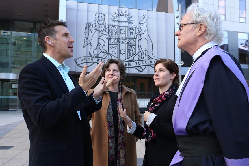 Alex Jones speaks in Auslan to a judge, a woman and interpreter outside Paramatta district court