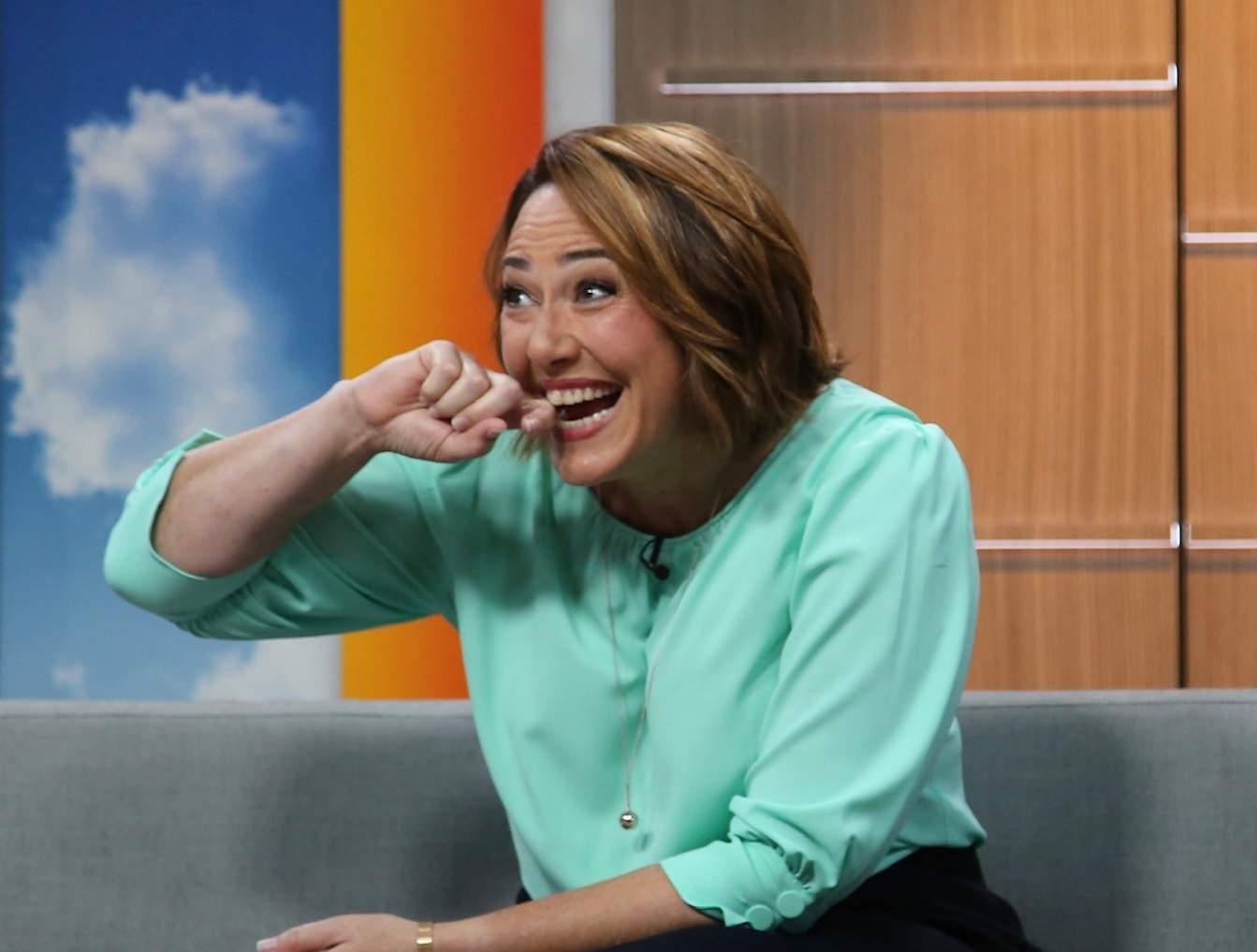 Lisa Millar grins and holds her hand to her mouth as she sits on the News Breakfast couch.