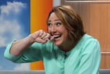Lisa Millar grins and holds her hand to her mouth as she sits on the News Breakfast couch.