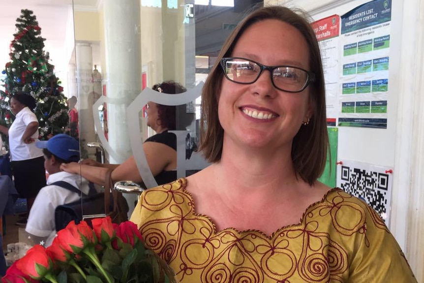 Gabrielle Maina holds a bunch of red roses.