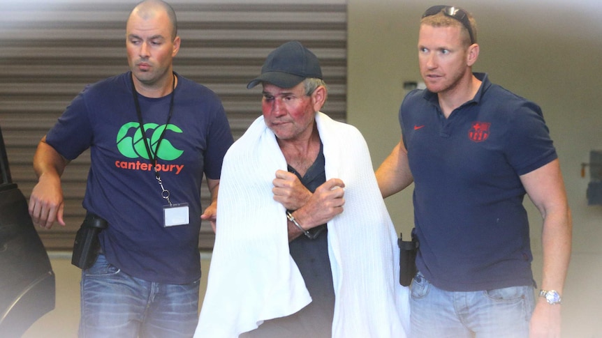 Gino Stocco is escorted by two policemen as he is taken into Dubbo police station