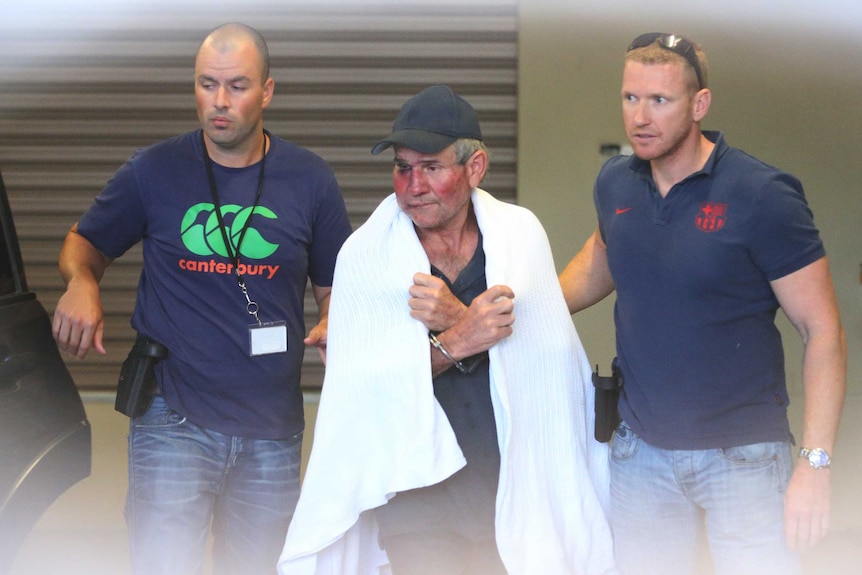 Gino Stocco is escorted by two policemen as he is taken into Dubbo police station