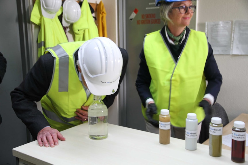 A man bends over to look at biodiesel.