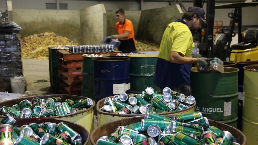 Two workers sort through waste at the opening of a Jandakot waste to energy plant in Perth WA.