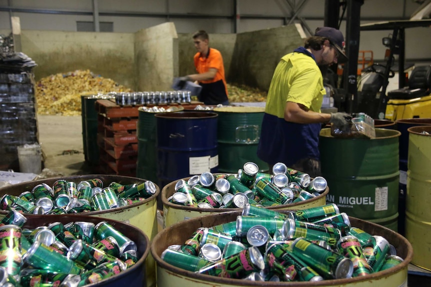 Two workers sort through waste at the opening of a Jandakot waste to energy plant in Perth WA.