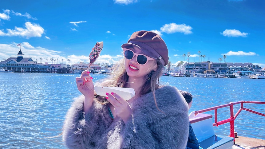 A woman standing on the seaside with an ice-cream in her hand