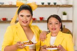 Aysha Buffett and her mum Josie Difuntorum hold a plate of chicken adobo each in a kitchen.