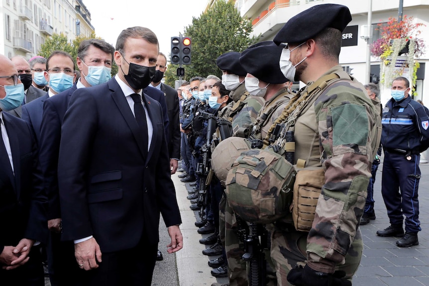 French President Emmanuel Macron stands opposite a line of soldiers near the site of the Nice attack.